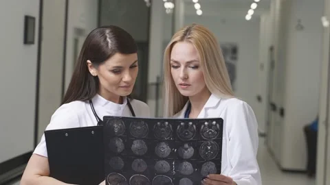 Two Young Doctors Looking At Computed Tomography X-ray Image, Discussing Stock Footage 150728530