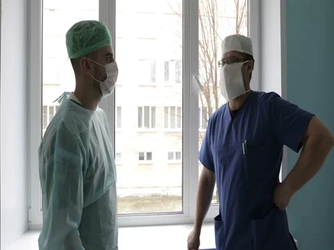 Two young doctors in medical uniforms and masks are talking in the hospital agai Stock Footage 73776676