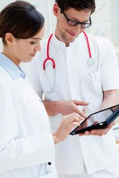 Two young doctors using digital tablet, smiling Stock Photos