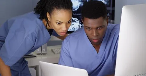 Two young doctors working together on multiple computers Foto stock