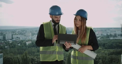 Two young engineers man and female have a discussion on the top of construction Stock Footage 92938540
