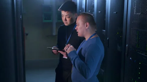 Two young engineers talking and doing network diagnostics in workflow at data Stock Footage 163816452