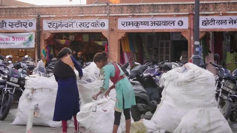 Two young female ragpickers drinking water, sorting plastic waste in city market Video stock 244953993