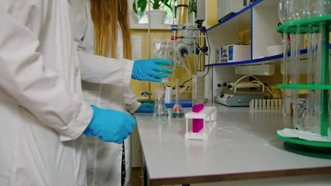 Two young female scientists doing research in a laboratory with colorful liquid Stockbeeldmateriaal 274959541
