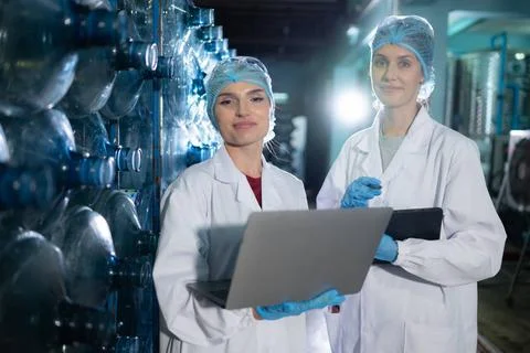 Two young female scientists working with tablet computer in drinking water... Stock Photos
