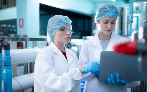 Two young female scientists working with tablet computer in drinking water... Stock Photos
