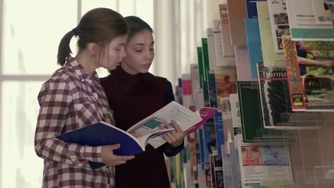 Two young female students focused on choosing books in library Stock-Footage 73313352
