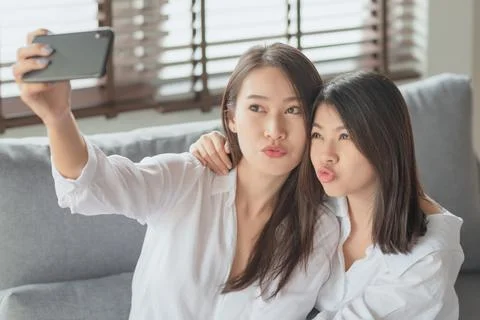 Two young female using mobile phone and internet technology to use video call Photos