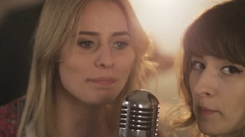 Two Young Female Vocalists Singing to the Microphone and Smiling Stock Footage 74490565