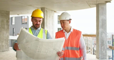 Two young foremen go along construction site and look at the blueprint Stock Footage 172286891
