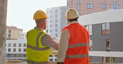 Two young foremen standing in the construction site and look at the blueprint Stock Footage 172287104