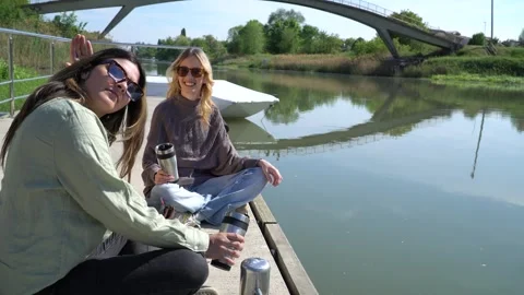 Two young friends are having a relaxing time over coffee on the dock Video stock 304177577