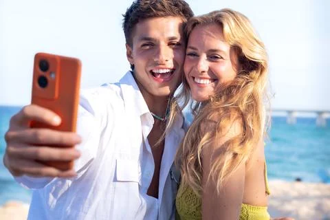 Two young friends on the beach doing a self portrait with the smartphone. Stock-Fotos
