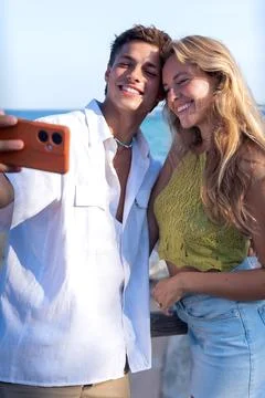 Two young friends on the beach doing a self portrait with the smartphone. Stock Photos