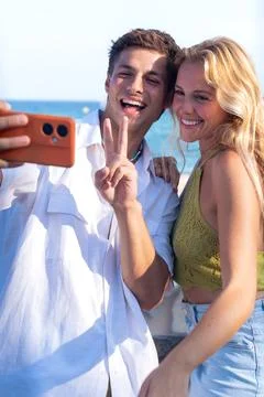 Two young friends on the beach making a video call with the smartphone. Stock Photos