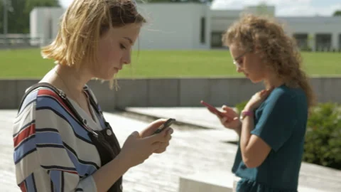 Two young friends chat using mobile phones. Video stock 132549783