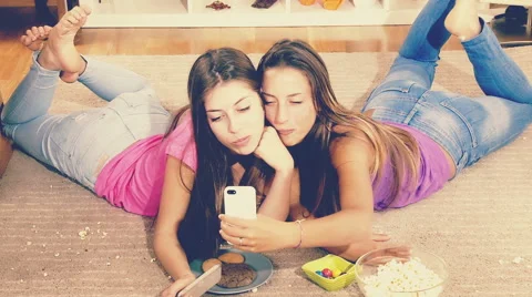 Two young friends eating trash food making selfie with phone laying on floor Stock Footage 51310214