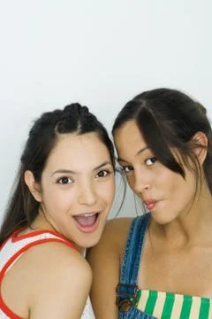 Two young friends looking at camera, one smiling, the other puckering lips 写真素材