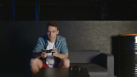 Two young friends playing action video game in the living room sitting on the Video stock 136331567