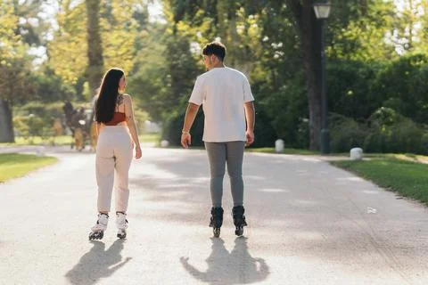 Two young friends skating with inline skates in a park Stock Photos