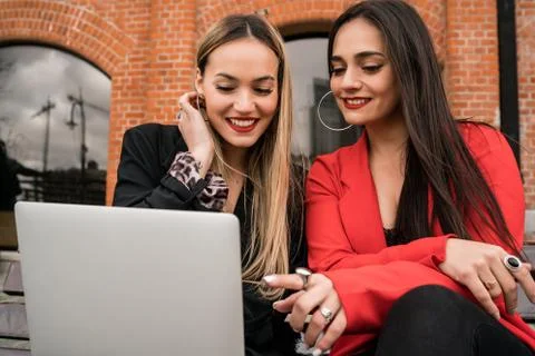 Two young friends using a laptop outdoors. Stock Photos