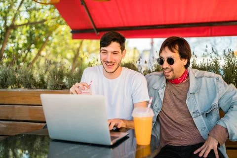 Two young friends using laptop at coffee shop. Stock Photos