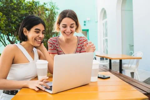 Two young friends using a laptop at coffee shop. Stock Photos