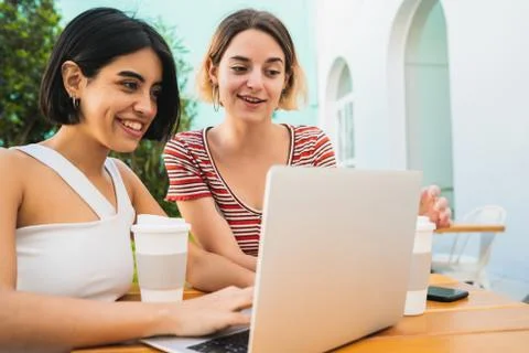 Two young friends using a laptop at coffee shop. Stock Photos