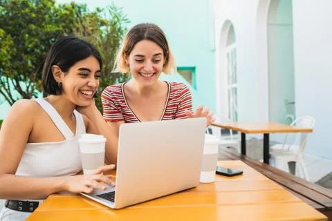 Two young friends using a laptop at coffee shop. Stock Photos