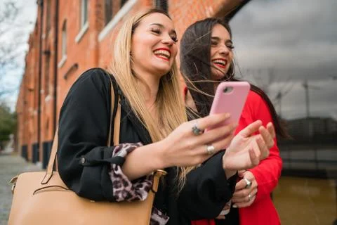 Two young friends using their mobile phone outdoors. Foto stock