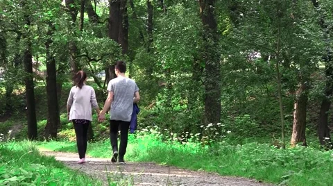 Two young, a girl and a boy walking in an alley in the park. Boy ride a bike  Stock Footage 59757255