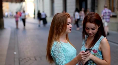 Two young girl using GPS in mobile phone. Old town backbround. Stock Footage 55142544