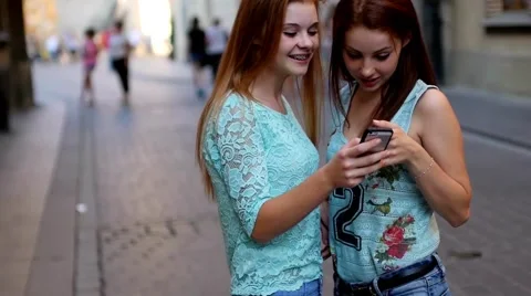 Two young girl using GPS in mobile phone. Old town backbround. Stock Footage 55142565