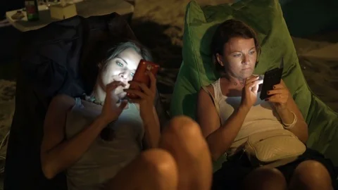 Two young girlfriends using smartphone in outdoor cafe, 4K Stock Footage 70573075