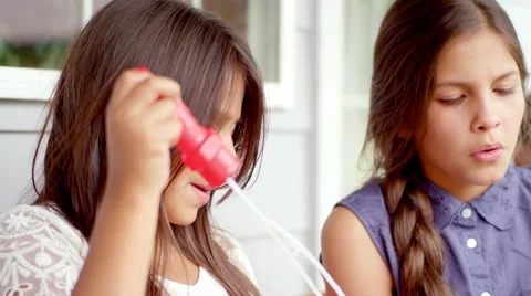 Two young girls blow bubbles at each other, in slow motion Video stock 47784053