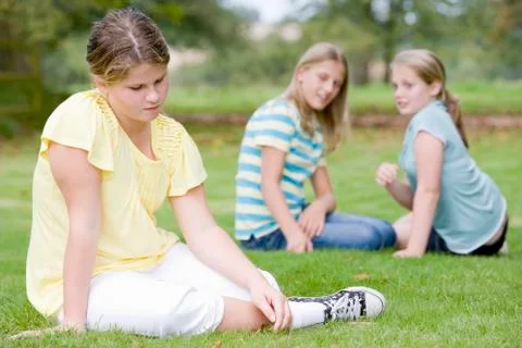 Two young girls bullying other young girl outdoors Stock Photos