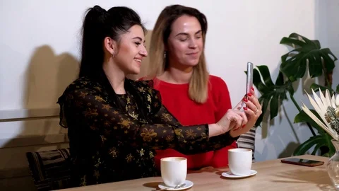 Two Young Girls Chating in Internet Using Smart Phone Wireless Online In a Cafe. Video stock 125525361