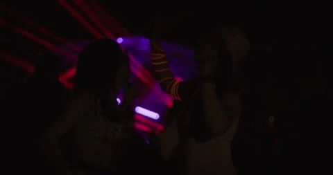Two young girls dancing and jumping in crowd in front of stage. Low light video Stock Footage 313654893