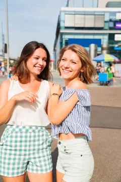 Two young girls friends walk in city in summer day Stock Photos