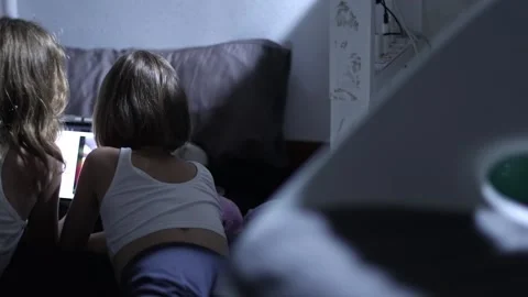 Two young girls lying on a soft floor surrounded by pillows and a blanket Stock Footage 313539541