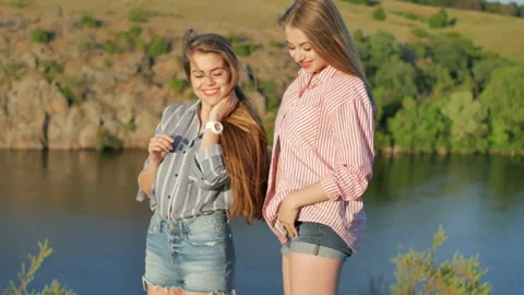 Two young girls posing on the camera on the riverbank Stock Footage 89298971