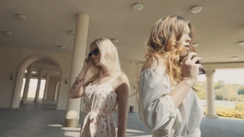 Two young girls posing in front of the camera on the background of architectural Stock Footage 104480104