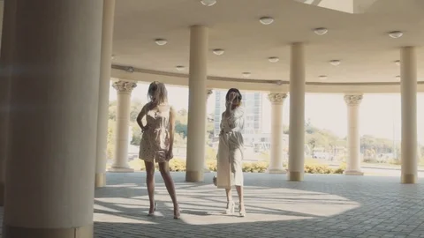 Two young girls posing in front of the camera on the background of architectural Stock Footage 104480341