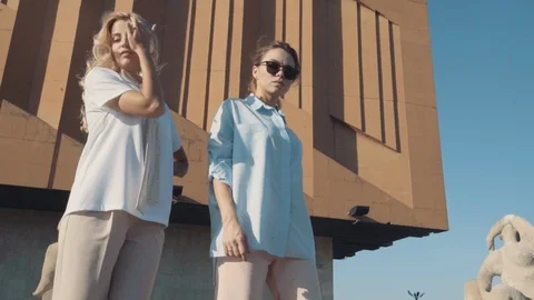 Two young girls posing in front of the camera on the background of architecture. Stock Footage 104504006