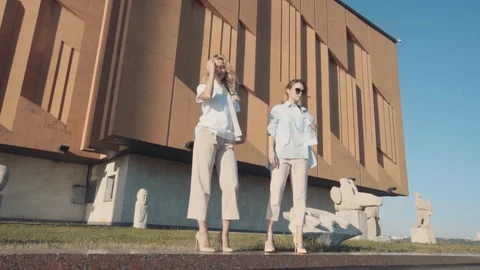 Two young girls posing in front of the camera on the background of architecture. Stock Footage 104504271