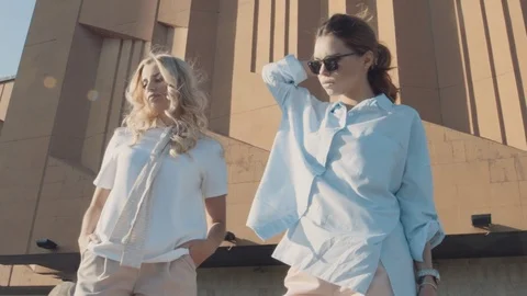 Two young girls posing in front of the camera on the background of architecture. Stock Footage 104504895