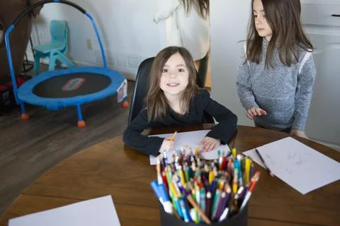 Two young girls at a table doing schoolwork. Stock Photos