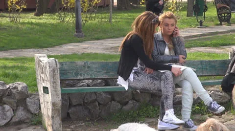 Two young girls talking on the cellphone.Reading a magazine. 스톡 동영상 22993237