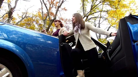 Two young girls teasing guy while he is pushing a car Stock Footage 48379195