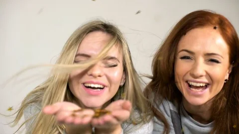 Two young girls throw confetti on a white background Stock Footage 70776993